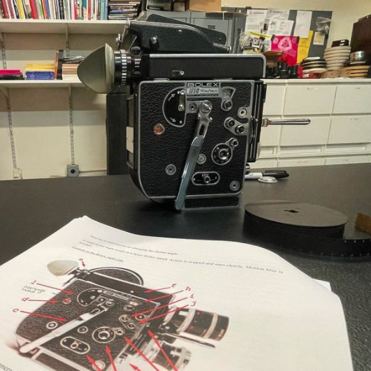Bolex camera on a table with notes.
