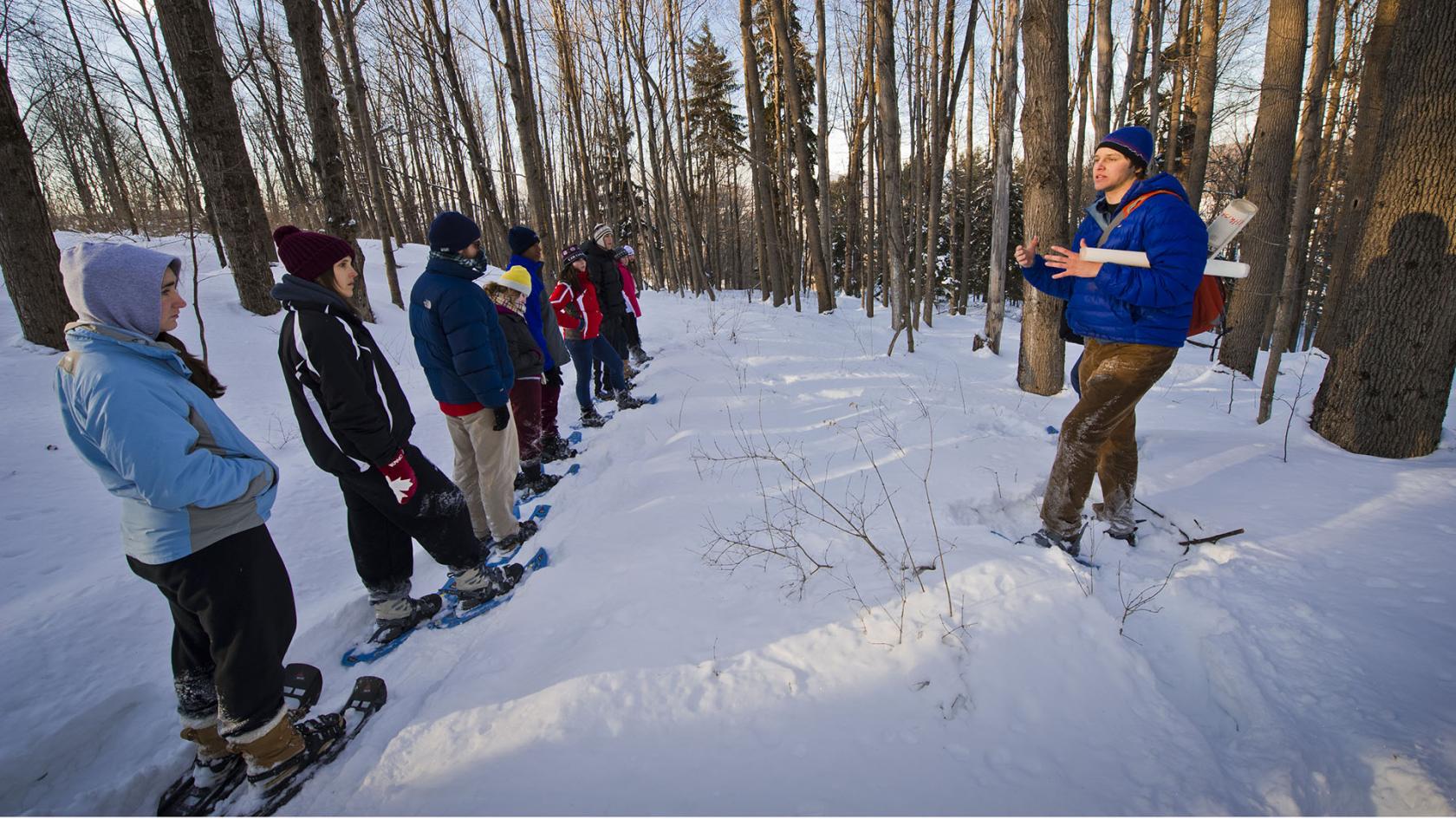 A group of people standing in the snow with snowshoes