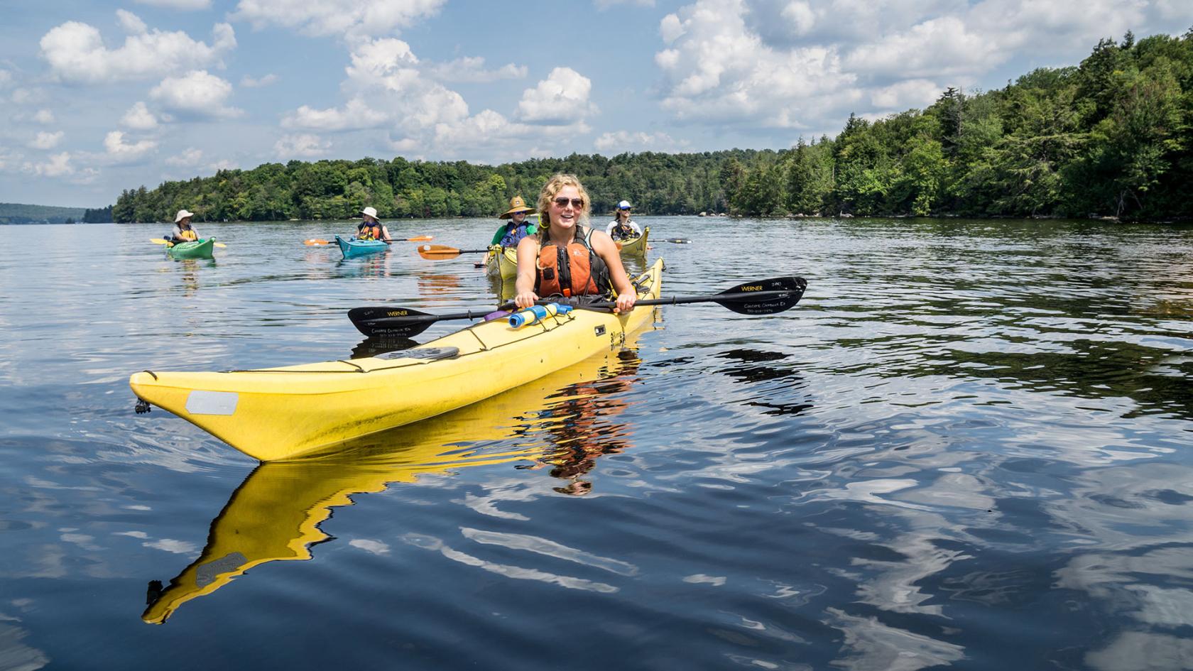 A group of people kayak on a lake