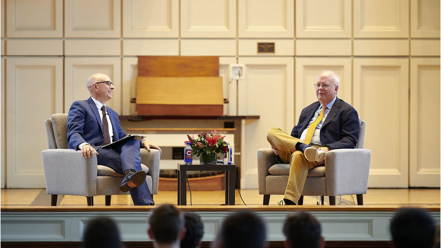 Two people sitting on a stage talking