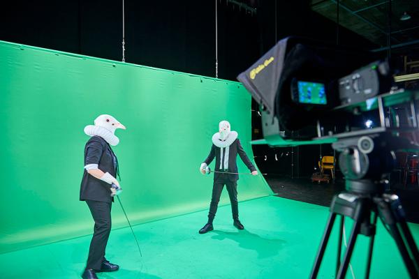 Two students in costume performing in front of green screen